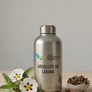 Stainless steel water bottle with a green leaf logo and the text 'Just Different People' next to a white flower bouquet and a bowl of dried fruits on a wooden surface.