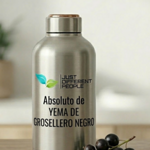 Stainless steel bottle with the brand name Just Different People and the Spanish label 'Absoluto de Yema de Grosellero Negro,' beside a small cluster of black grapes on a table.