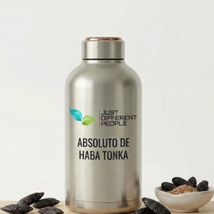 Stainless steel bottle with 'ABSOLUTO DE HABA TONKA' branding and Just Different People logo, surrounded by tonka beans and a small bowl of brown sugar.